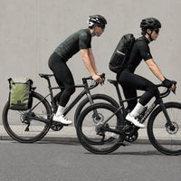 Deux cyclistes sur route, le modèle vert fixé au porte-bagages et le modèle noir porté sur le dos