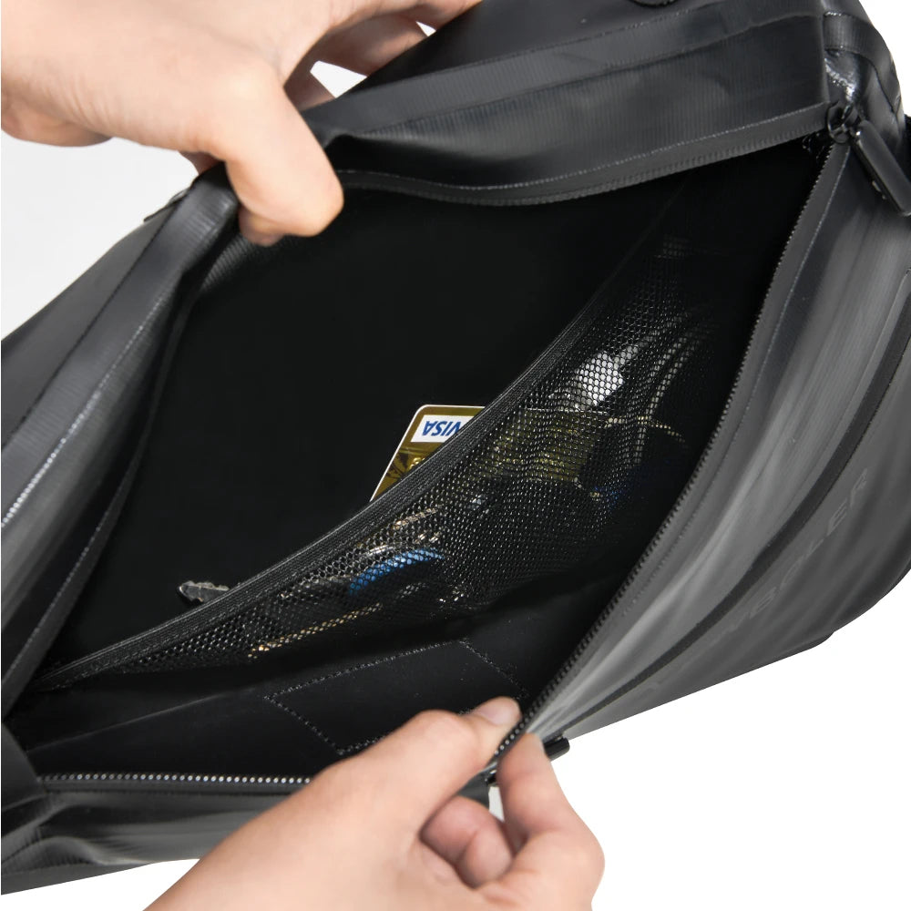 Interieur d'une sacoche de velo noire ouverte, montrant une poche en filet avec une carte bancaire.