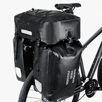 Triple sacoche de porte-bagage noire fixée sur le porte-bagage arrière d'un vélo gris avec bandes réfléchissantes