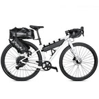 Velo blanc equipe d'un kit complet de sacoches de bikepacking : sacoche de selle, de cadre, de fourche et de guidon.