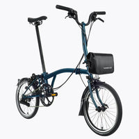 Velo pliant bleu avec sacoche de cadre noire installee, presente de profil sur fond blanc.