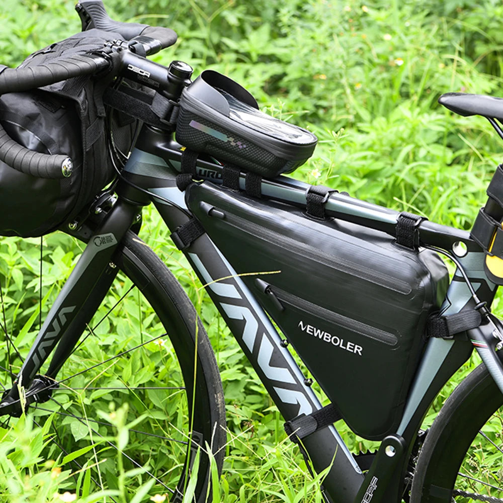 Velo de route avec sacoche de cadre triangulaire et sacoche de guidon noires installees, devant une vegetation verte.